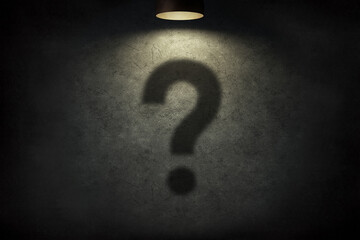 Question mark design with spotlight on textured black wall background