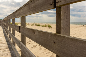Wooden railings at the decking running along the seashore.