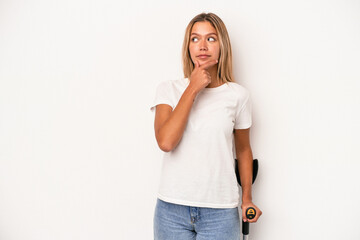 Young caucasian woman holding crutch isolated on white background looking sideways with doubtful...