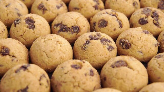 Small round dessert cookies with chocolate chips stacked in rows. Macro. Slow rotation