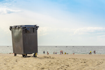 A large garbage can standing on the sea beach.