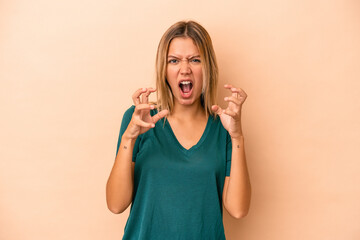 Young caucasian woman isolated on beige background screaming with rage.