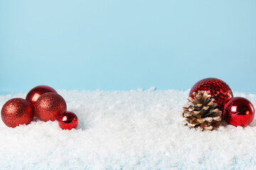 red christmas ornament in snow on blue background. copy space