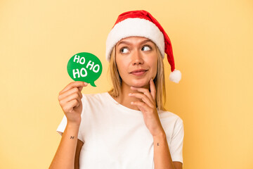 Young caucasian woman holding a christmas props isolated on yellow background