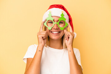 Young caucasian woman holding a christmas props isolated on yellow background