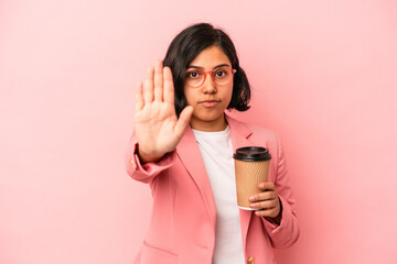 Young latin woman holding take away coffee isolated on pink background standing with outstretched hand showing stop sign, preventing you.