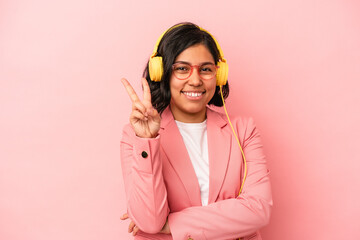 Young latin woman listening to music isolated on pink background showing number two with fingers.