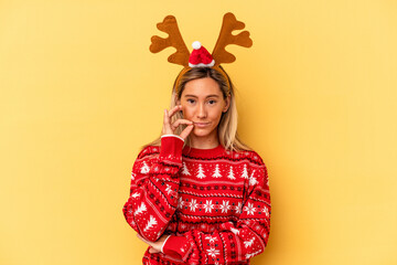 Young caucasian woman wearing a christmas reindeer hat isolated on beige background with fingers on lips keeping a secret.