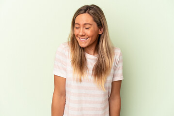 Obraz premium Young caucasian woman isolated on green background laughs and closes eyes, feels relaxed and happy.