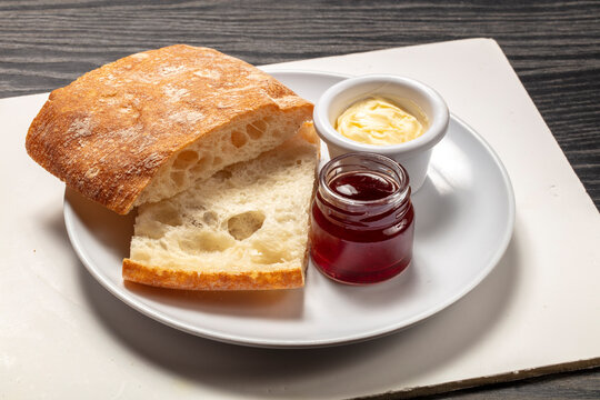 Desayuno, pan con mantequilla y mermelada de fresa sobre bandeja y fondo de madera. Breakfast, bread with butter and strawberry jam.