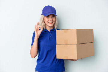 Young delivery caucasian woman isolated on blue background cheerful and confident showing ok gesture.