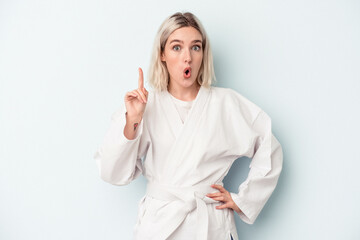 Fototapeta premium Young caucasian woman doing karate isolated on blue background having some great idea, concept of creativity.