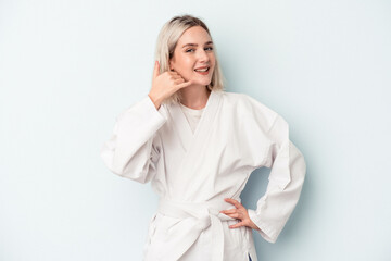 Young caucasian woman doing karate isolated on blue background showing a mobile phone call gesture...