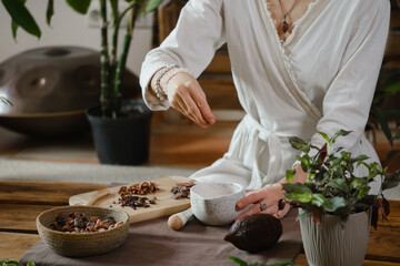 Cacao ceremony in atmospheric space with green plants and candles. Woman making ritual healthy...