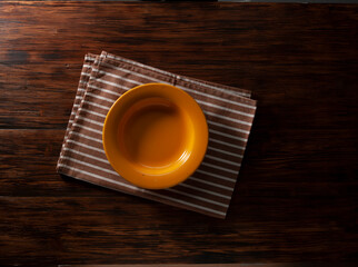 Plato vacío  naranja sobre servilleta y fondo de madera. Orange empty plate on napkin and wooden background.
