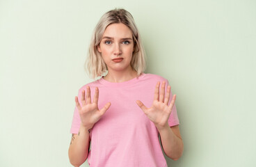 Young caucasian woman isolated on green background rejecting someone showing a gesture of disgust.