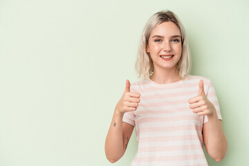 Young caucasian woman isolated on green background smiling and raising thumb up