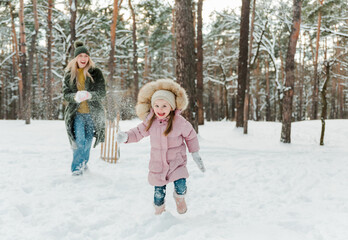 Fototapeta na wymiar Happy and smilling young mother and her little daughter having fun outside, in winter park