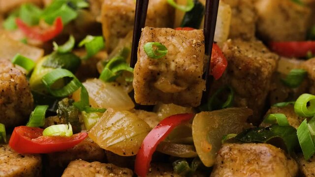 Picking Crispy salt and pepper Tofu from a bowl using a chopstick. Asian Vegan Food