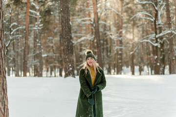 Pretty young blond woman, dressed warmly, with a scarf and mittens. Beautiful girl having fun in...