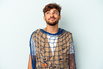 Young mixed race fisherman holding a net isolated on blue background dreaming of achieving goals...