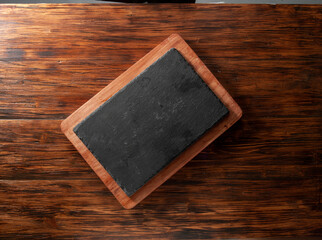 Tabla de cortar de pizarra sobre mesa de madera. Slate cutting board on wooden table.