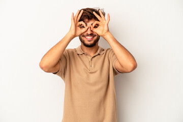 Young mixed race man isolated on grey background showing okay sign over eyes