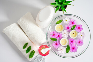 Face and body care products with pink flowers. Freshness and body care. Skin cosmetics. White clear towels for purity