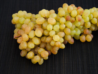 Bunch of rose Sultana grapes on black napkin background
