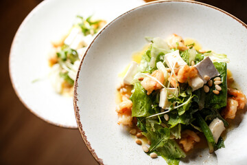 two salads with shrimps and cheese on white plates