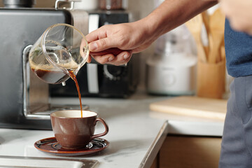 Man pouring dark coffee he made in the morning in cup
