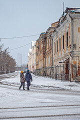 A man and a woman approach a historic building for restoration on a cold winter day