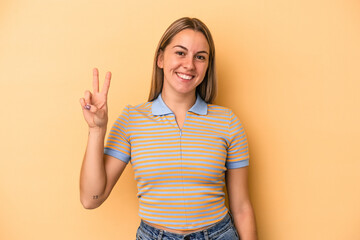 Young caucasian woman isolated on yellow background joyful and carefree showing a peace symbol with fingers.