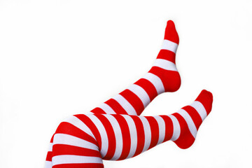 Female legs in Christmas knee socks on white background. Concept of New Year celebration, girl in stockings with red and white stripes