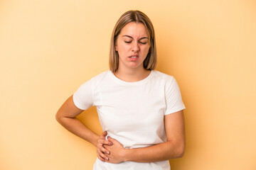 Young caucasian woman isolated on yellow background having a liver pain, stomach ache.