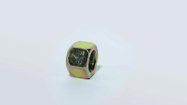 The metal nut rotates on a white background. Golden nut on a white background close-up