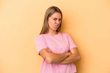 Fototapeta premium Young caucasian woman isolated on yellow background frowning face in displeasure, keeps arms folded.
