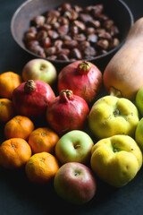 Pan with chestnuts, butternut squash and various fruit on dark background. Selective focus.