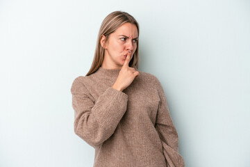 Young caucasian woman isolated on blue background keeping a secret or asking for silence.