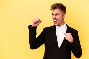 Young caucasian business man isolated on yellow background raising fist after a victory, winner concept.