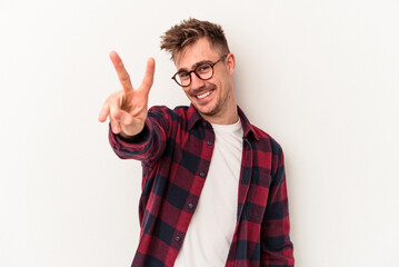 Young caucasian man isolated on white background joyful and carefree showing a peace symbol with fingers.