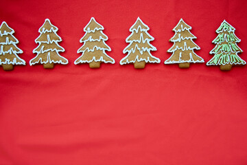 Fototapeta na wymiar Christmas handmade gingerbread cookies with copy space on red fabric background. Christmas trees cookies. Festive card with minimalist Christmas atmosphere. Merry Christmas and home coziness concept