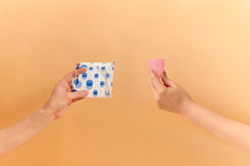 Menstrual cup and sanitary pad in hands. Feminine hygiene alternative product instead of tampon during her period. Menstruation, critical days, zero waste, eco, ecology concept.
