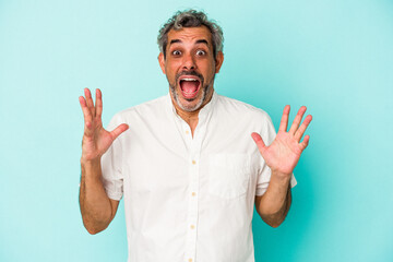 Middle age caucasian man isolated on blue background  celebrating a victory or success, he is surprised and shocked.