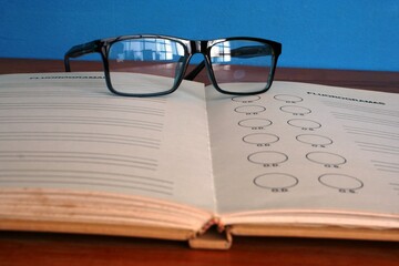 Los lentes sobre las hojas del libro para estudiar en el colegio con fondo azul.