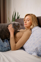 Pets, morning, comfort, rest and people concept - happy young woman with cat in bed at home