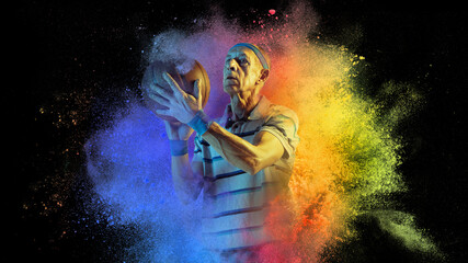 Artwork. Senior age sportsman, basketball player in explosion of colored neon powder isolated on dark background