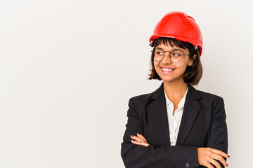 Young architect woman with red helmet isolated on white background smiling confident with crossed arms.