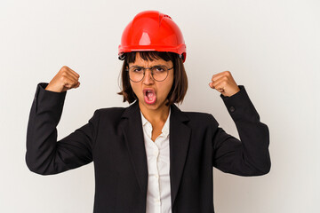 Young architect woman with red helmet isolated on white background showing strength gesture with arms, symbol of feminine power
