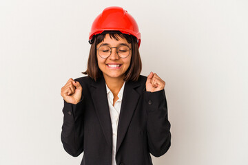 Young architect woman with red helmet isolated on white background raising fist, feeling happy and successful. Victory concept.